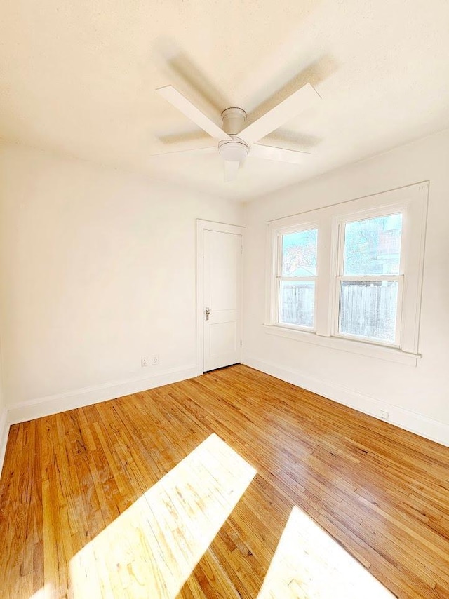 unfurnished room featuring ceiling fan, wood finished floors, and baseboards