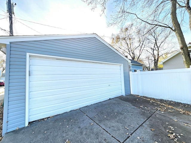 detached garage with concrete driveway and fence