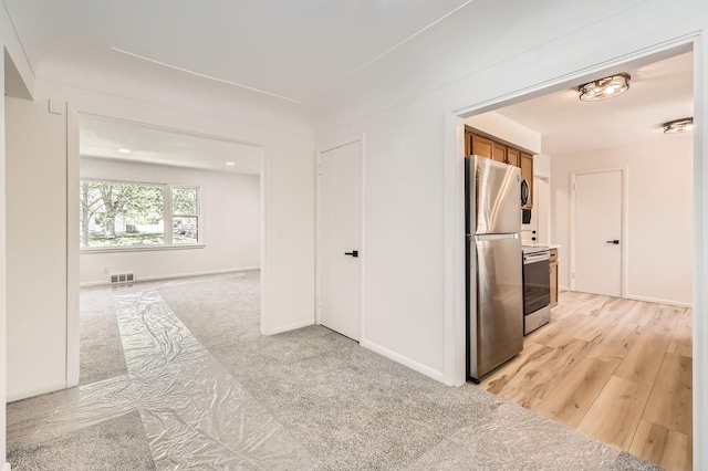 hall featuring baseboards and light colored carpet