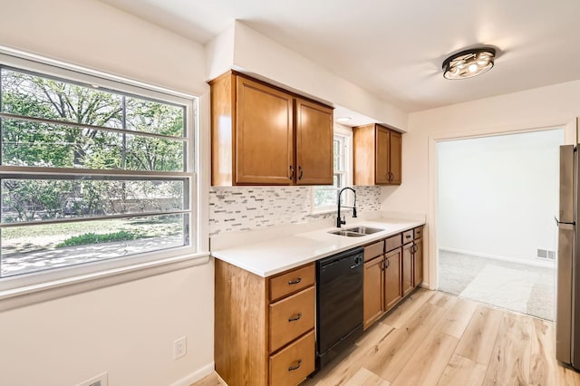 kitchen with a sink, dishwasher, light wood-style flooring, and healthy amount of natural light