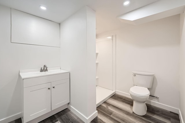 full bathroom with wood finished floors, toilet, baseboards, vanity, and a shower stall