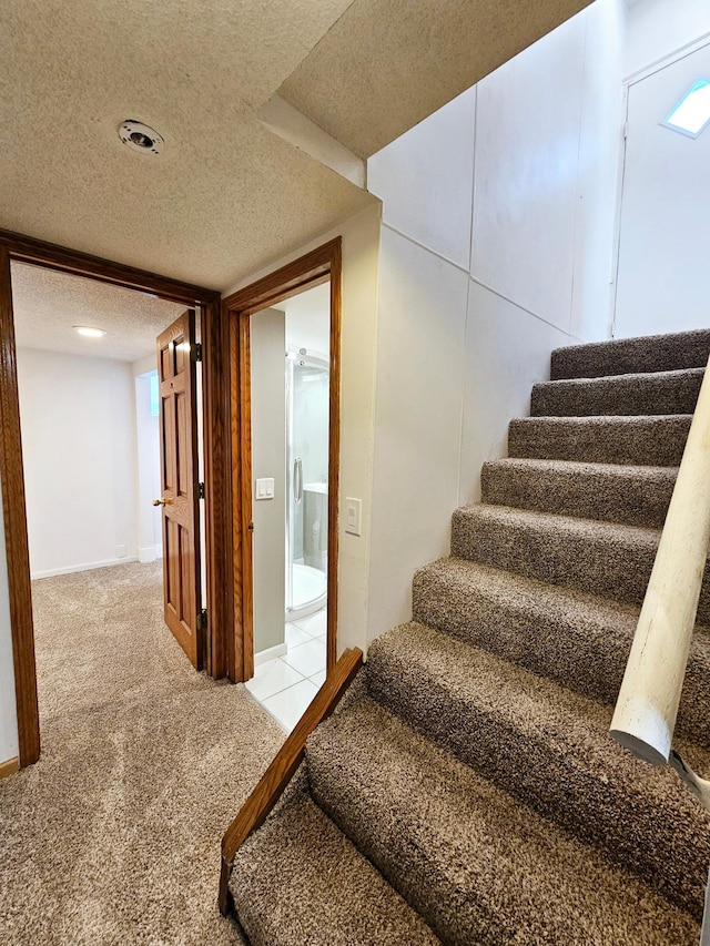 staircase featuring carpet and a textured ceiling