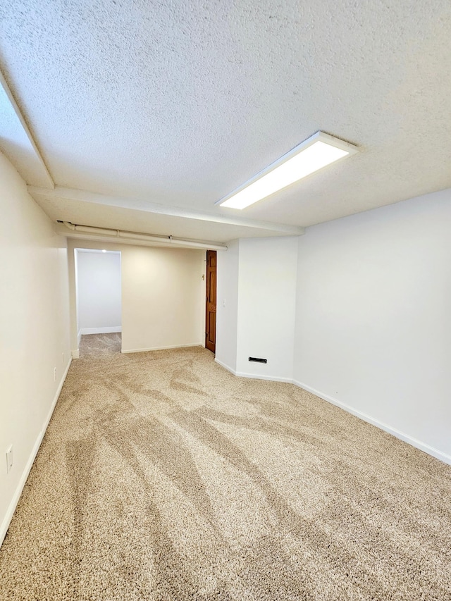 carpeted spare room with a textured ceiling and baseboards