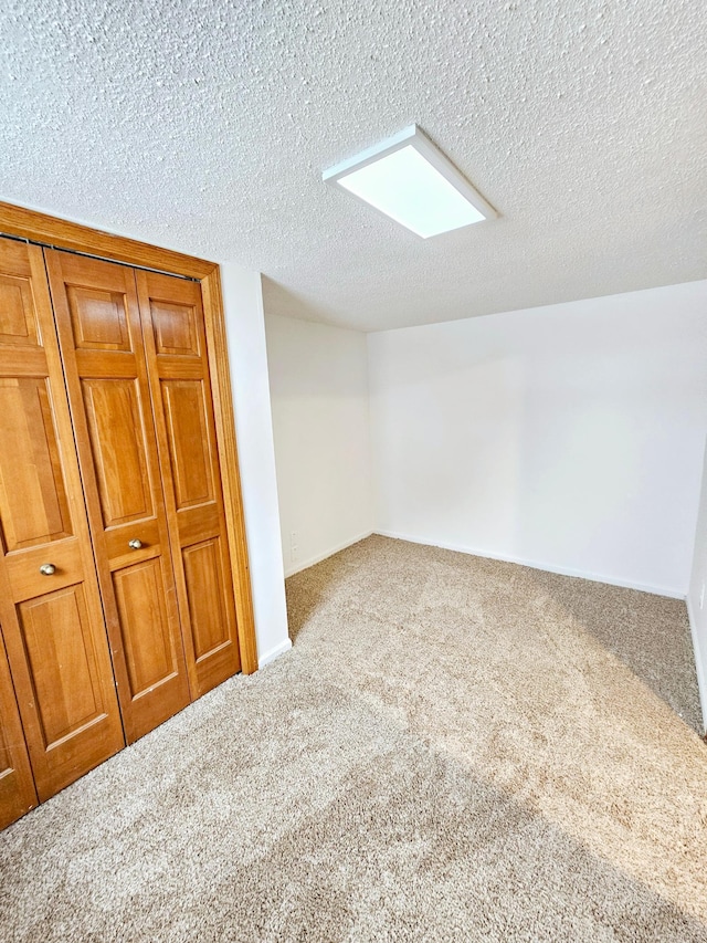 interior space with a textured ceiling, carpet, and baseboards