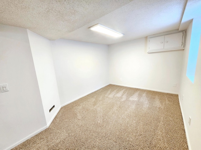 finished below grade area featuring carpet floors, baseboards, and a textured ceiling