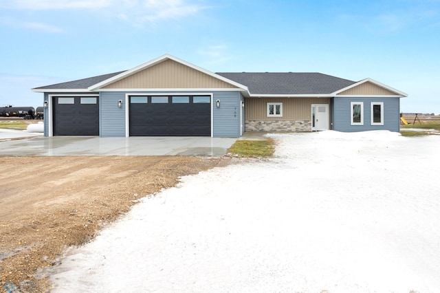 single story home featuring an attached garage, driveway, a shingled roof, and stone siding