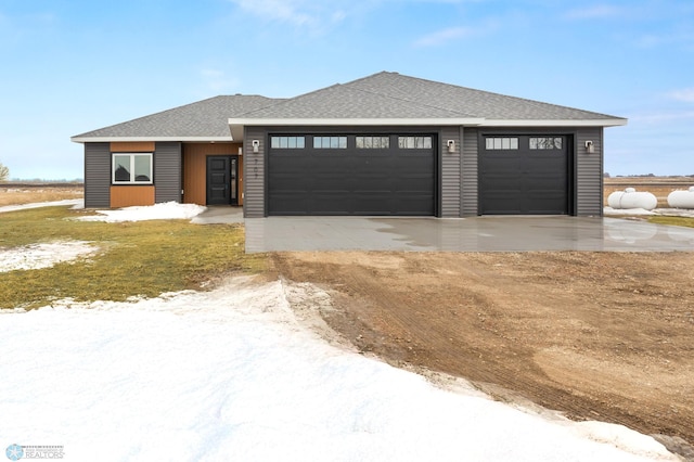 prairie-style house featuring driveway, an attached garage, and roof with shingles