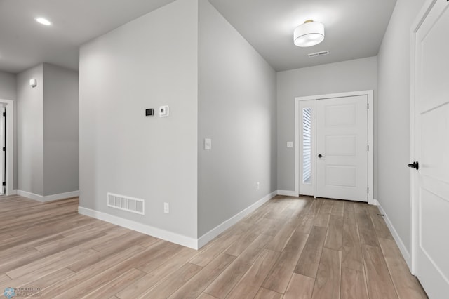 foyer with light wood-style floors, visible vents, and baseboards