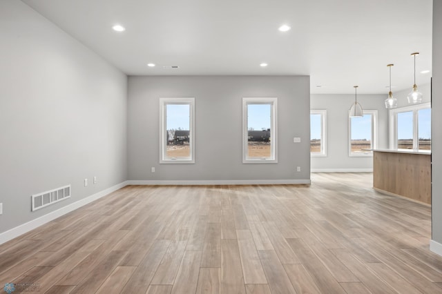 unfurnished living room featuring a wealth of natural light, visible vents, light wood-style flooring, and recessed lighting