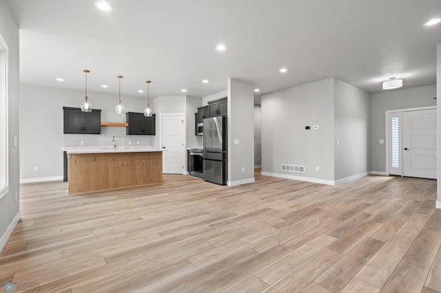 kitchen with visible vents, appliances with stainless steel finishes, open floor plan, light countertops, and a sink