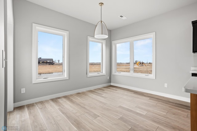 unfurnished dining area featuring baseboards, visible vents, and light wood-style floors