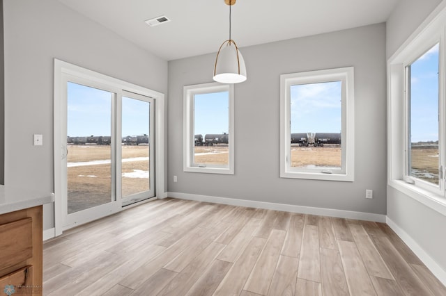 unfurnished dining area featuring light wood finished floors, baseboards, and visible vents