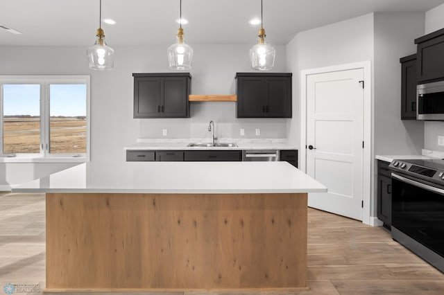 kitchen with light countertops, appliances with stainless steel finishes, a sink, and a center island