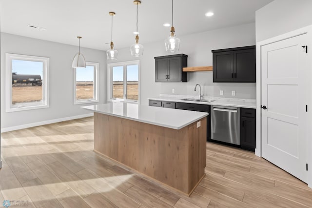 kitchen with light countertops, dark cabinetry, a center island, dishwasher, and pendant lighting