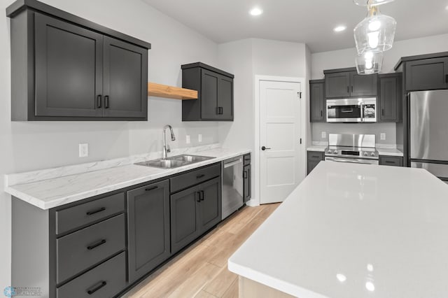 kitchen with open shelves, light countertops, appliances with stainless steel finishes, light wood-style floors, and a sink