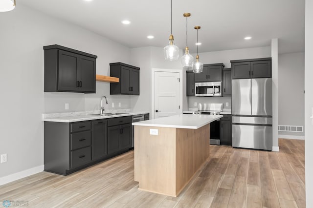 kitchen featuring a sink, stainless steel appliances, light countertops, and a center island