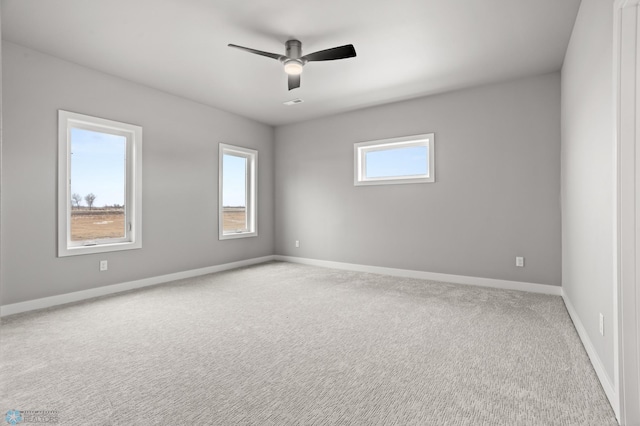 empty room with carpet floors, plenty of natural light, a ceiling fan, and baseboards