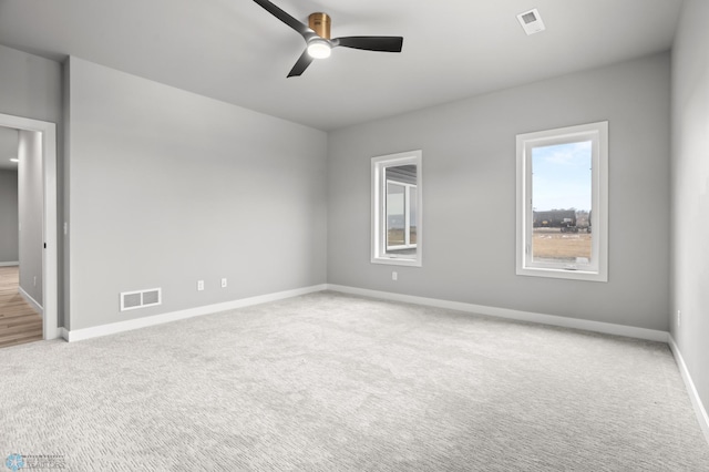 unfurnished room with baseboards, visible vents, a ceiling fan, and light colored carpet