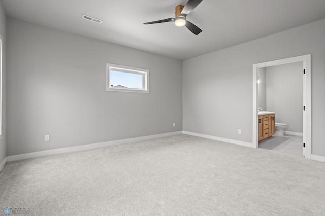 unfurnished bedroom featuring ceiling fan, connected bathroom, light colored carpet, visible vents, and baseboards