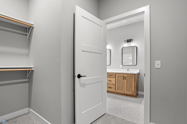 bathroom featuring baseboards, a walk in closet, and vanity