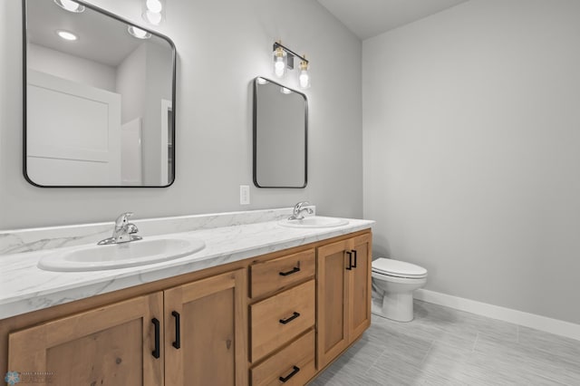 full bath featuring double vanity, baseboards, toilet, and a sink