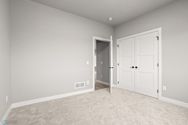 unfurnished bedroom featuring baseboards, a closet, visible vents, and carpet flooring