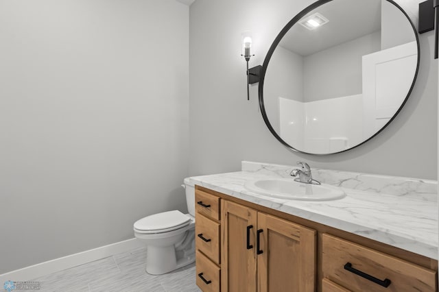 bathroom featuring toilet, vanity, and baseboards