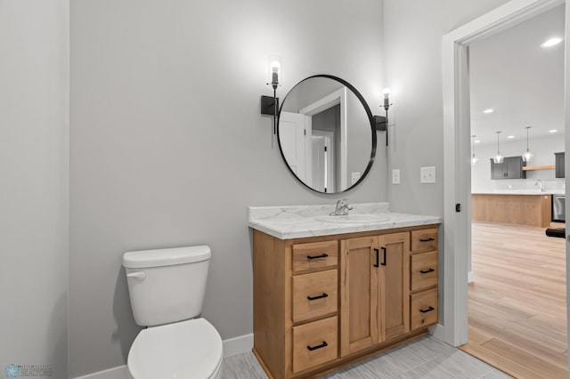 bathroom featuring recessed lighting, toilet, vanity, wood finished floors, and baseboards