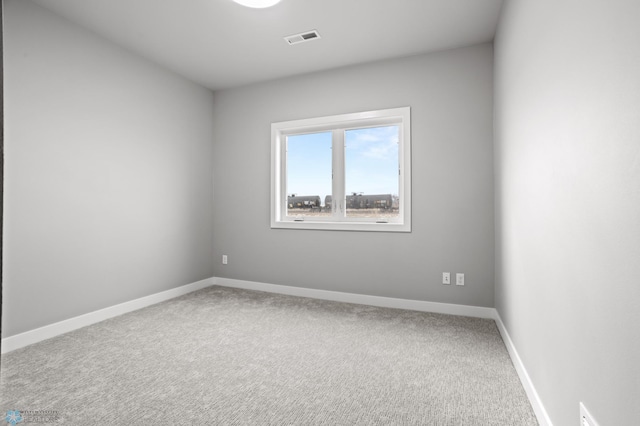 carpeted spare room featuring visible vents and baseboards