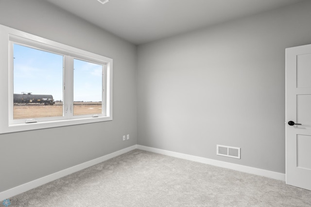 spare room featuring carpet, visible vents, and baseboards