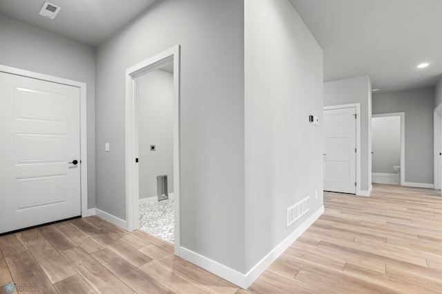 hallway featuring visible vents, light wood-style flooring, and baseboards