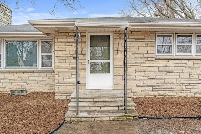 doorway to property with a shingled roof, stone siding, a chimney, and crawl space