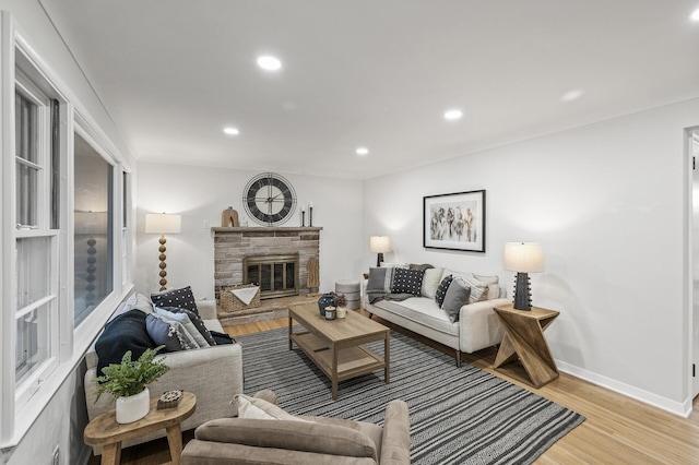 living room with light wood-type flooring, a stone fireplace, baseboards, and recessed lighting