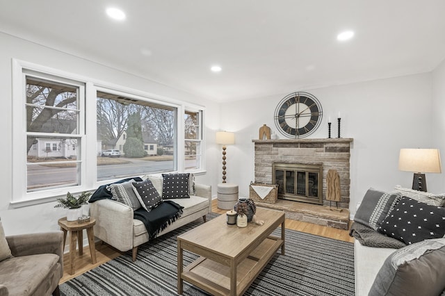 living area with a stone fireplace, wood finished floors, and recessed lighting