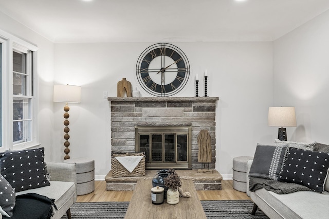 living room with a brick fireplace, wood finished floors, and baseboards