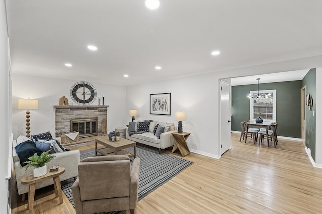 living area with recessed lighting, baseboards, a fireplace, and light wood finished floors