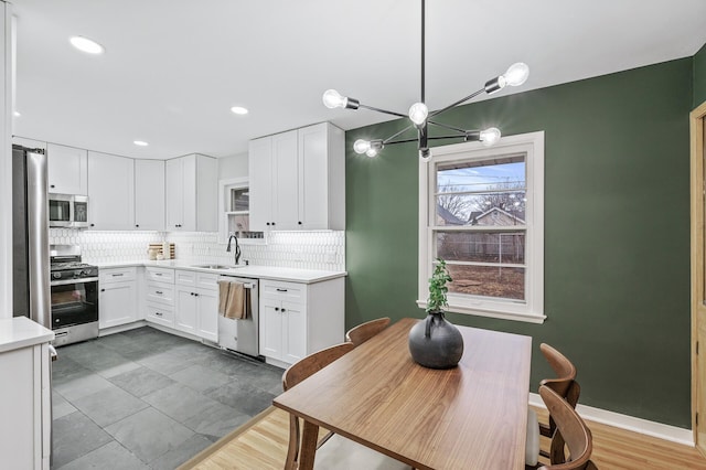 kitchen featuring a sink, stainless steel appliances, light countertops, white cabinetry, and backsplash