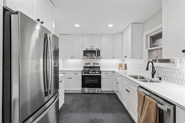 kitchen featuring appliances with stainless steel finishes, backsplash, a sink, and white cabinets