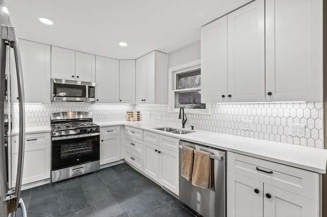 kitchen featuring tasteful backsplash, stainless steel appliances, light countertops, white cabinetry, and a sink