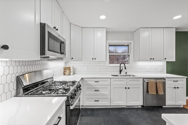 kitchen with stainless steel appliances, a sink, light countertops, and white cabinets