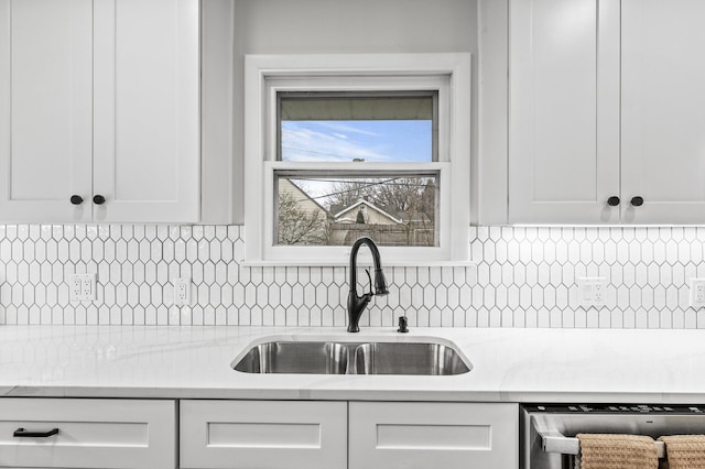 kitchen featuring dishwasher, backsplash, white cabinets, and a sink