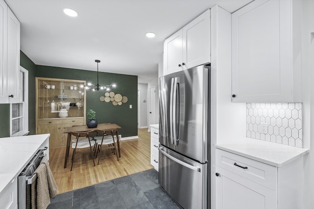 kitchen featuring pendant lighting, recessed lighting, decorative backsplash, freestanding refrigerator, and white cabinets