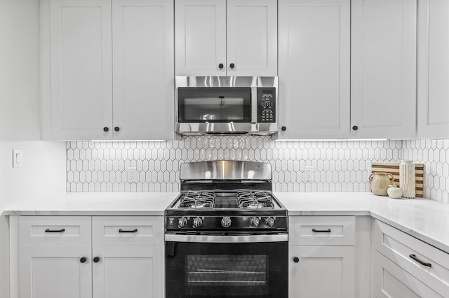 kitchen featuring white cabinets, stainless steel microwave, and black range with gas stovetop