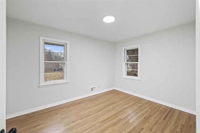 unfurnished room featuring light wood-type flooring, visible vents, and baseboards