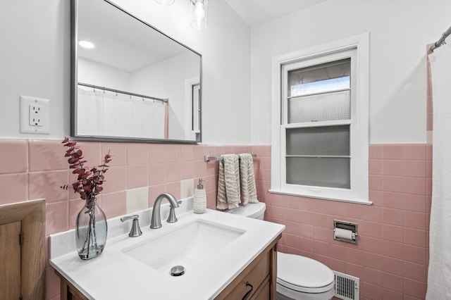 bathroom featuring tile walls, visible vents, vanity, and toilet