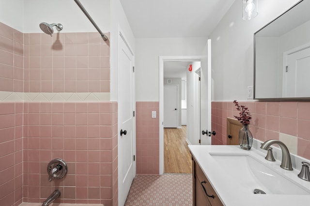 full bath with washtub / shower combination, wainscoting, tile walls, and vanity