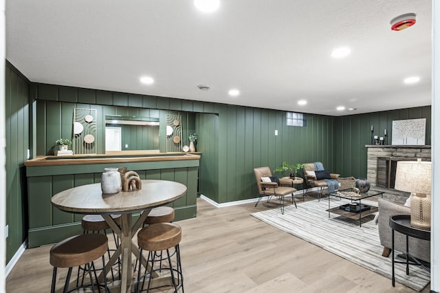 interior space featuring recessed lighting, a fireplace, a bar, and wood finished floors