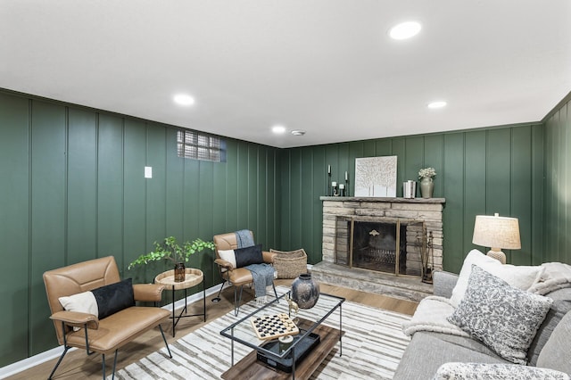 living room with recessed lighting, a stone fireplace, baseboards, and wood finished floors