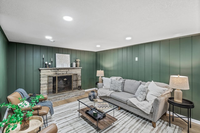 living area featuring recessed lighting, baseboards, wood finished floors, and a stone fireplace