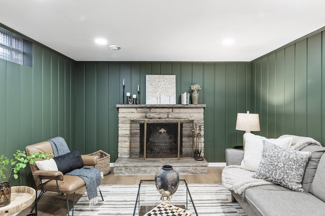 living room featuring a stone fireplace and wood finished floors